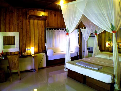 a bedroom with two beds and a window with curtains at Bunaken Cha Cha Nature Resort in Bunaken