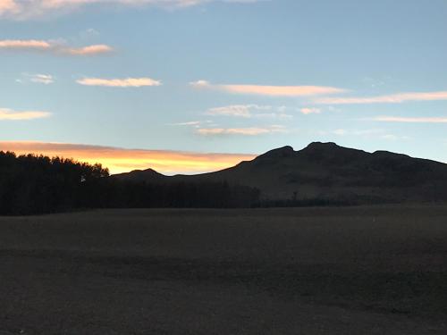 a sunset over a field with a mountain in the background at Billerwell B&B in Hawick