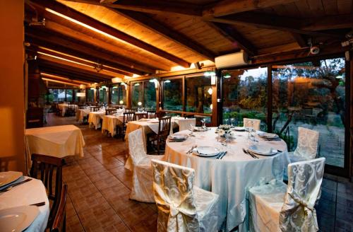 um salão de banquetes com mesas e cadeiras brancas e janelas em Il Borgo sul Lago em Pizzo