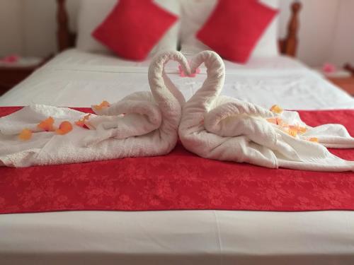 2 cigni fatti di asciugamani su un letto di Pension Hibiscus a La Digue