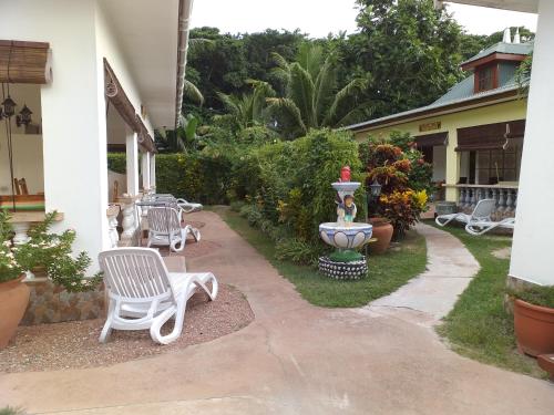 a patio with chairs and a fountain in a yard at Pension Hibiscus in La Digue