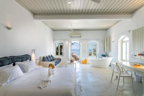 a bedroom with a large white bed and a tub at Samaria by the Sea in Khóra Sfakíon