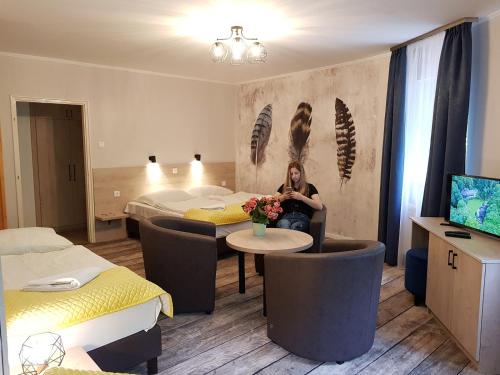 a woman is sitting in a hotel room at Erdővarázs Panzió in Lillafüred