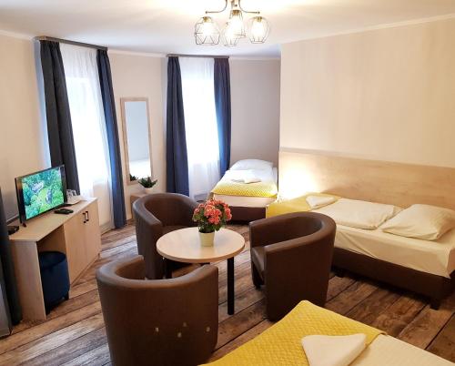 a hotel room with two beds and a table and chairs at Erdővarázs Panzió in Lillafüred