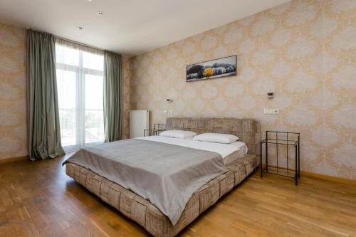 a bedroom with a large bed and a large window at Tbilisi Apartment in Tbilisi City