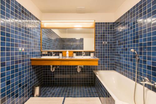Baño de azulejos azules con bañera y espejo en Vintage Duplex in Bruges en Brujas