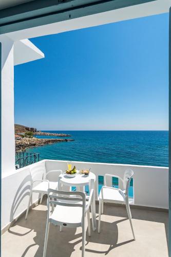 a white table and chairs on a balcony with the ocean at Livikon by the Sea in Khóra Sfakíon