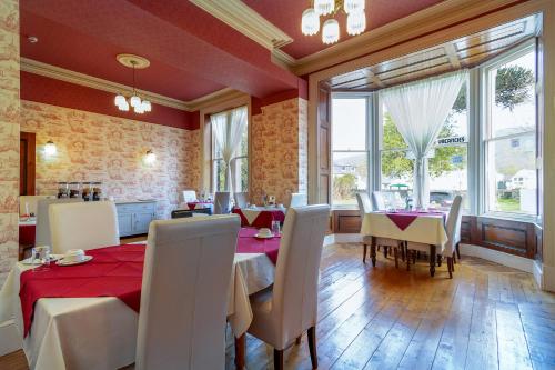 a dining room with tables and chairs and windows at Dolafon Guest House in Llanberis