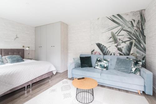 een woonkamer met een blauwe bank en een bed bij Rafa przy Plaży in Sztutowo