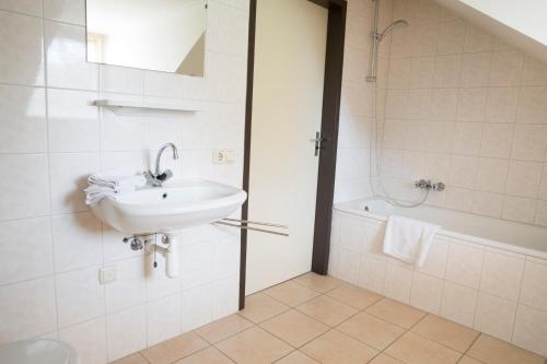 a white bathroom with a sink and a shower at Boerenhuuske in Margraten