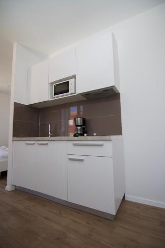 a kitchen with white cabinets and a microwave at Apartments and Rooms Jospino in Mali Lošinj