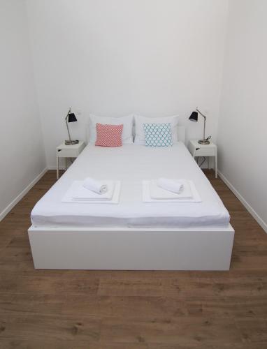 a large white bed in a room with two tables at Apartments and Rooms Jospino in Mali Lošinj