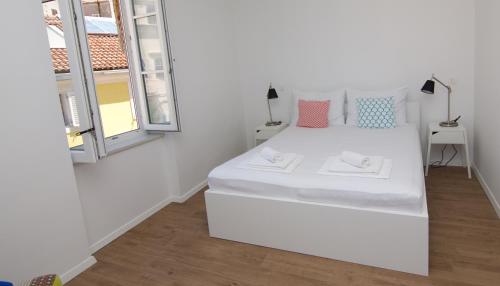 a white bed in a room with a window at Apartments and Rooms Jospino in Mali Lošinj