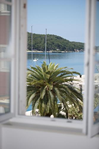a view of a palm tree from a window at Apartments and Rooms Jospino in Mali Lošinj