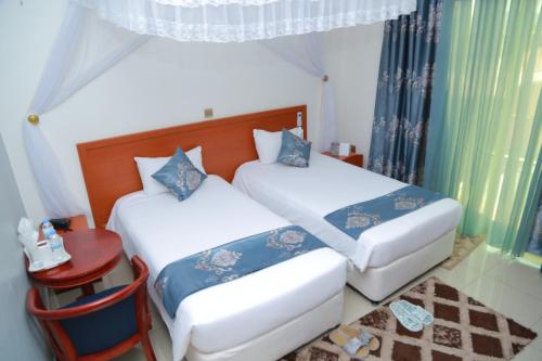 a bedroom with two beds and a table and a window at Lebanon Hotel in Kigali