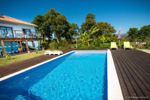 a swimming pool with two chairs and a house at Gîte CANTO AZUL in Casal da Carreira