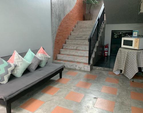a living room with a couch and stairs with a microwave at Isayarada Apartment in Thalang