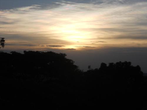 a sunset in the sky with trees in the foreground at Masaka Backpackers, Tourists Cottage & Campsite in Masaka