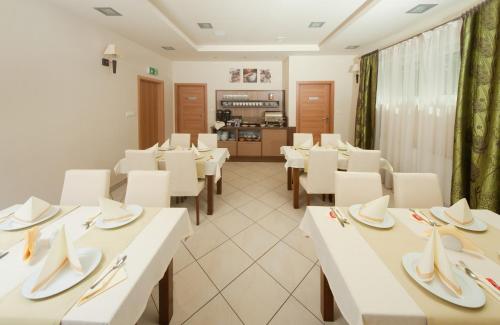 a dining room with white tables and white chairs at Hotel Zielony in Poznań