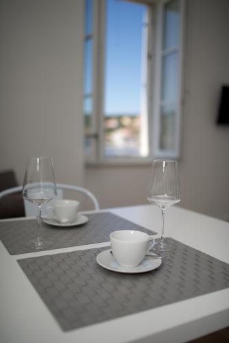 a table with two wine glasses and a cup and saucer at Apartments and Rooms Jospino in Mali Lošinj
