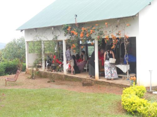 a group of people sitting on the porch of a house at Masaka Backpackers, Tourists Cottage & Campsite in Masaka