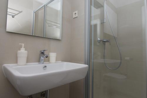 a white bathroom with a sink and a shower at Apartments and Rooms Jospino in Mali Lošinj