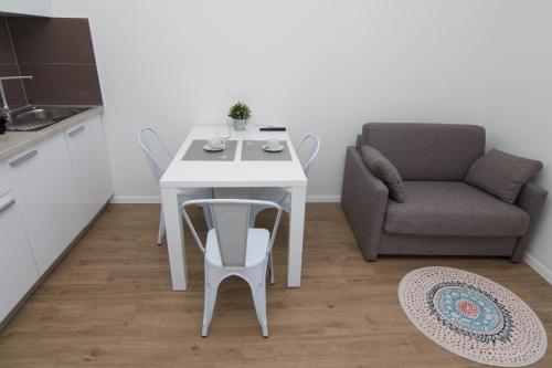 a white table and chair in a kitchen with a couch at Apartments and Rooms Jospino in Mali Lošinj