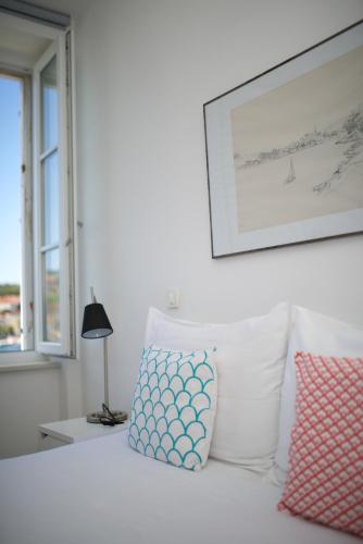 a bed with two pillows and a picture on the wall at Apartments and Rooms Jospino in Mali Lošinj
