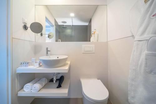 a bathroom with a sink and a toilet and a mirror at Allegro Madeira - Adults Only in Funchal