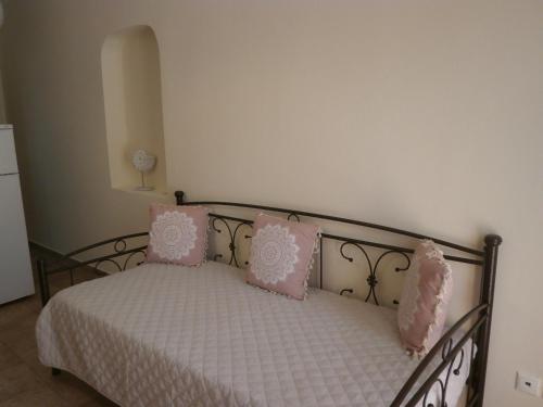 a bedroom with a bed with pink and white pillows at Flisvos Apartments in Megalochori