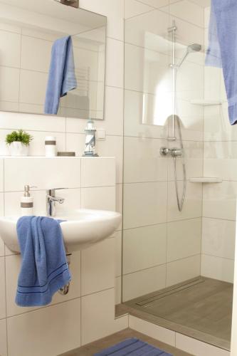 uma casa de banho com um lavatório e um chuveiro com toalhas azuis em Ferienwohnung Am Turm em Bad Staffelstein