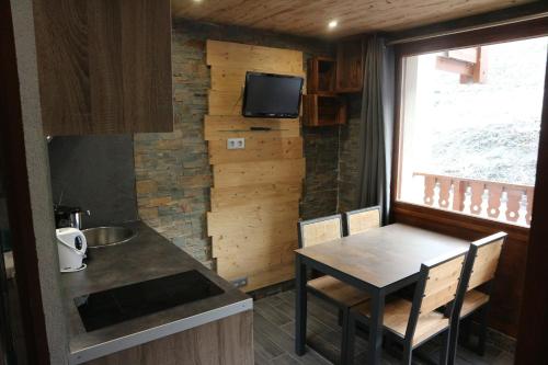 a kitchen with a table and a tv on a wall at Hameau du Borsat in Tignes