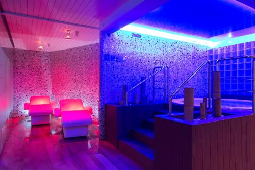 トッサ・デ・マールにあるGHT Oasis Tossa & Spaの椅子2脚と紫色の照明が備わる部屋