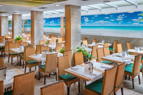 トッサ・デ・マールにあるGHT Oasis Tossa & Spaのテーブルと椅子、ビーチの壁画のあるレストラン