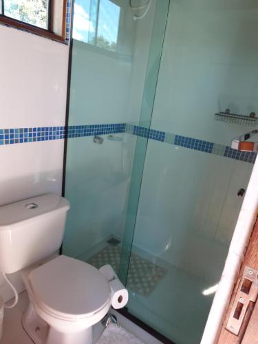 a bathroom with a toilet and a glass shower at Chalé Astral in Alto Paraíso de Goiás