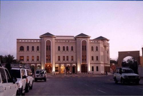 a large building with cars parked in front of it at Résidence El Arich in Tozeur