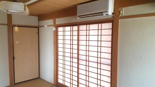 a room with a window and a door with a fan at Guest House Nakamura House in Oki