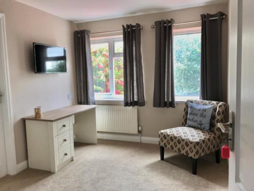 a bedroom with a desk and a chair and windows at Northorpe in Hornsea