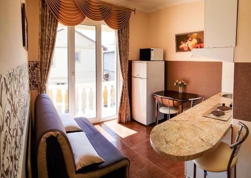 a living room with a kitchen with a table and a refrigerator at мини-отель Травертин in Chornomorsk