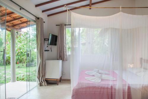 um quarto com uma cama rosa e uma janela em Pousada Peki em Arraial d'Ajuda