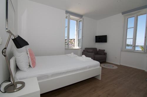 a white bedroom with a bed and a couch at Apartments and Rooms Jospino in Mali Lošinj