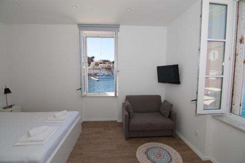 a room with a bed and a chair and a window at Apartments and Rooms Jospino in Mali Lošinj