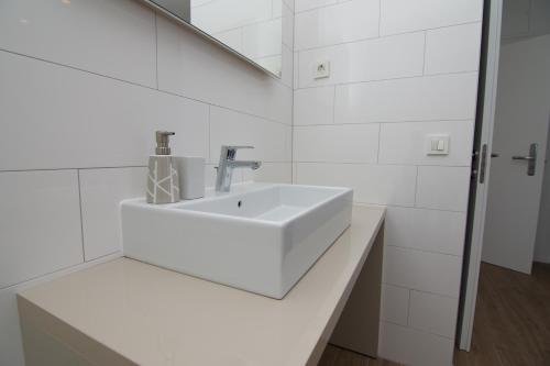 a white bathroom with a sink and a mirror at Apartments and Rooms Jospino in Mali Lošinj