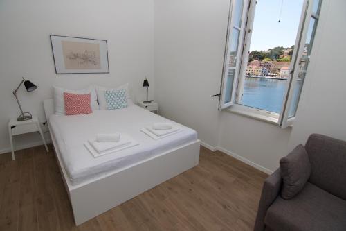 a white room with a bed and a window at Apartments and Rooms Jospino in Mali Lošinj