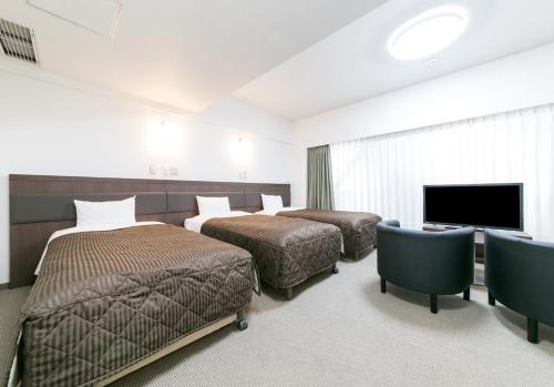 a hotel room with two beds and a flat screen tv at Pearl Hotel Kayabacho in Tokyo