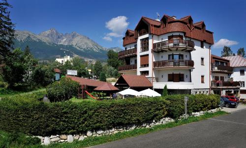 a large white building with a brown roof at APLEND Vila Beatrice in Vysoke Tatry - Tatranska Lomnica.