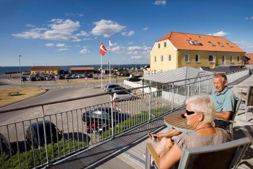 two people sitting on a balcony looking at a parking lot at Hvalpsund Færgekro in Hvalpsund