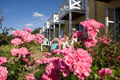two women sitting on the porch of a house with pink flowers at Hvalpsund Færgekro in Hvalpsund