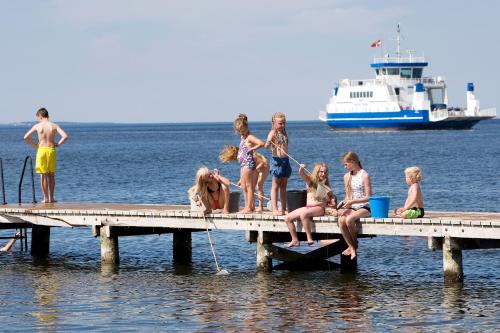 a group of children sitting on a dock in the water at Hvalpsund Færgekro in Hvalpsund