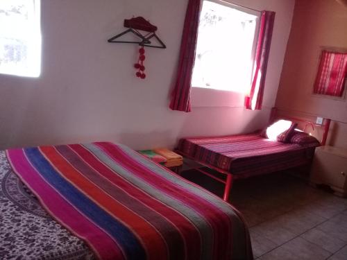 a bedroom with a bed and a window and a bench at Cabaña El Cardón,casita en el campo quebradeño in Humahuaca